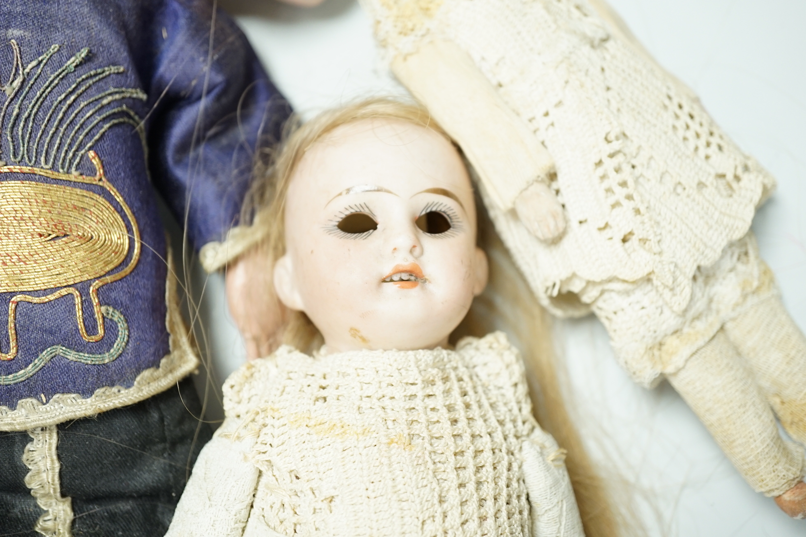 Two Chinese Papier mache dolls with embroidered silk clothing, a pair of Chinese embroidered silk slippers, a similar child’s bonnet a pair of Japanese slippers and three other dolls